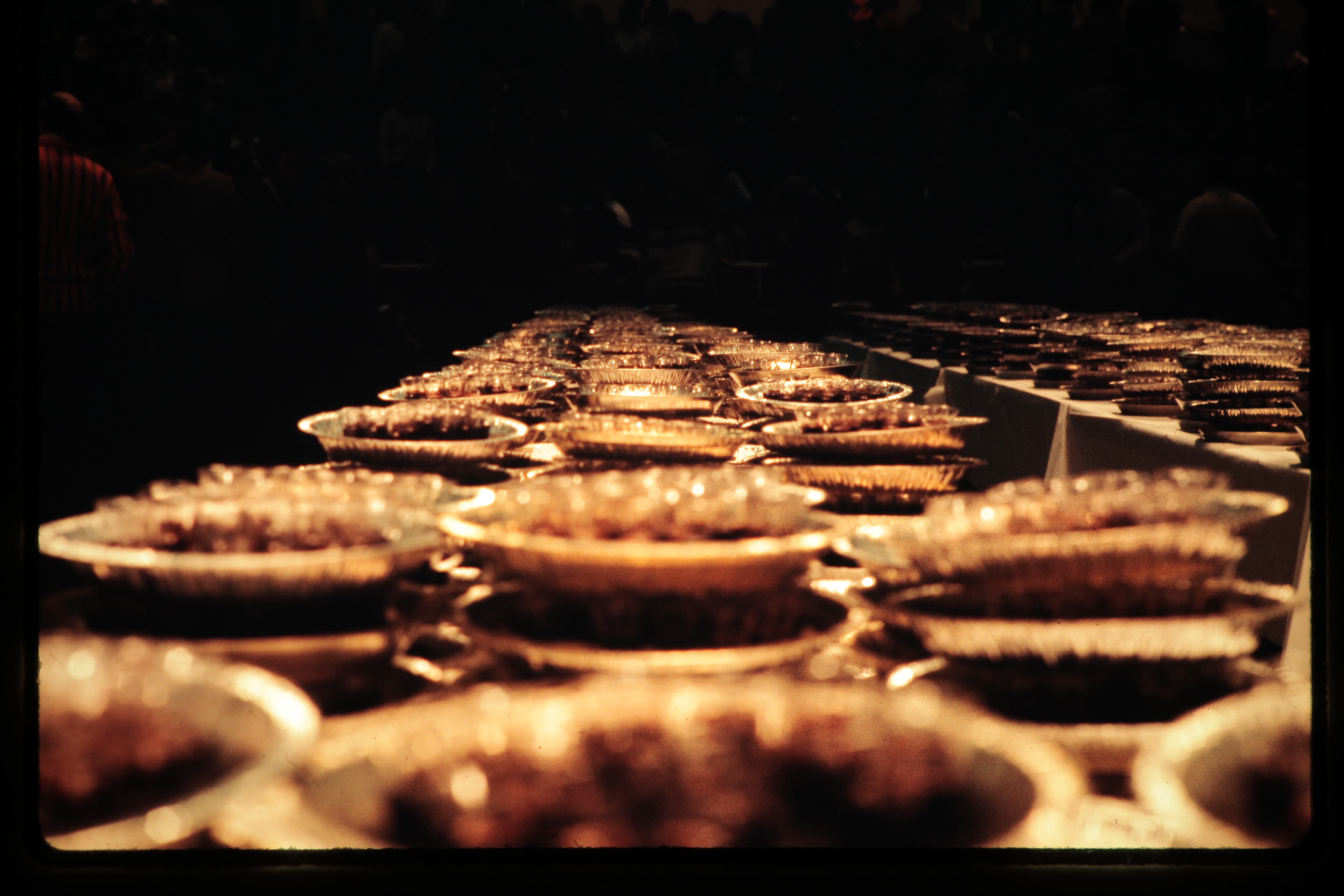 Rows of small bowls illuminated by warm light against a dark background