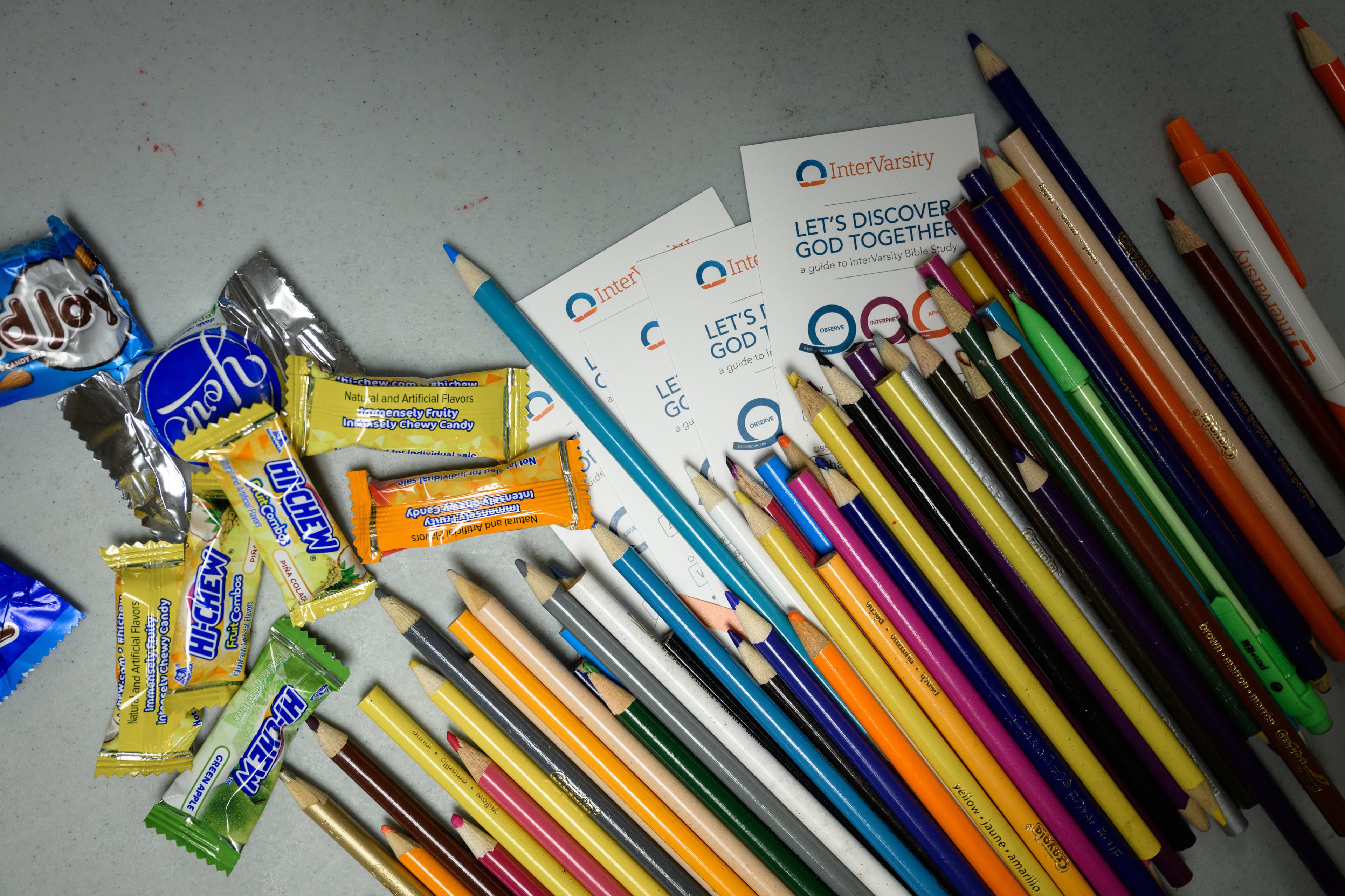 Colored pencils, candy, and InterVarsity cards arranged on a table