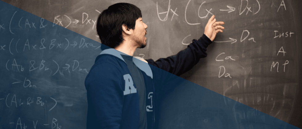 A person writing notes on a chalkboard in a classroom.