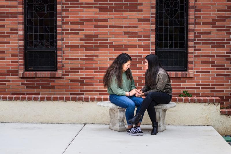 two girls are sitting next to the wall