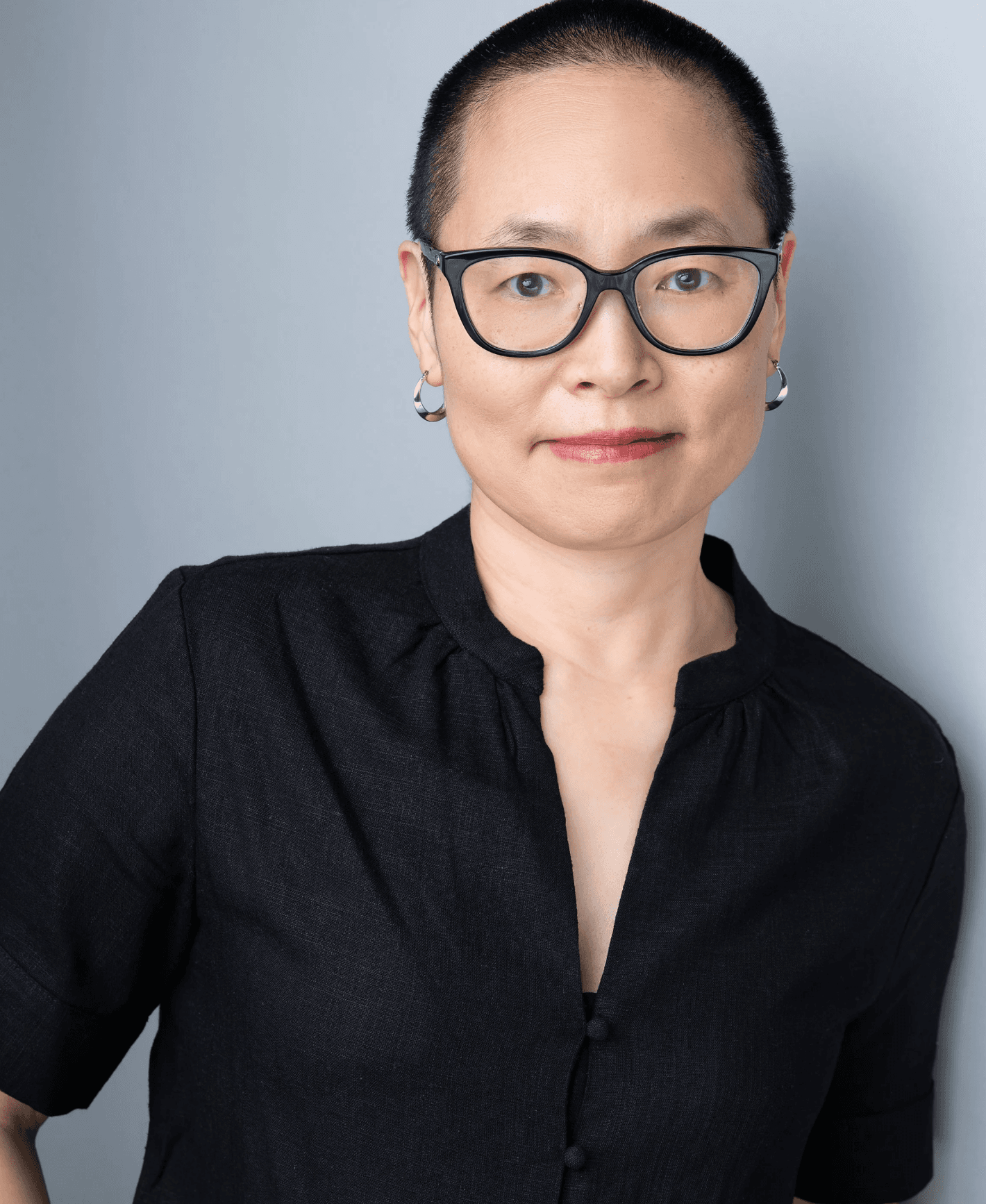 Portrait of a woman wearing glasses and a black blouse against a light gray background.
