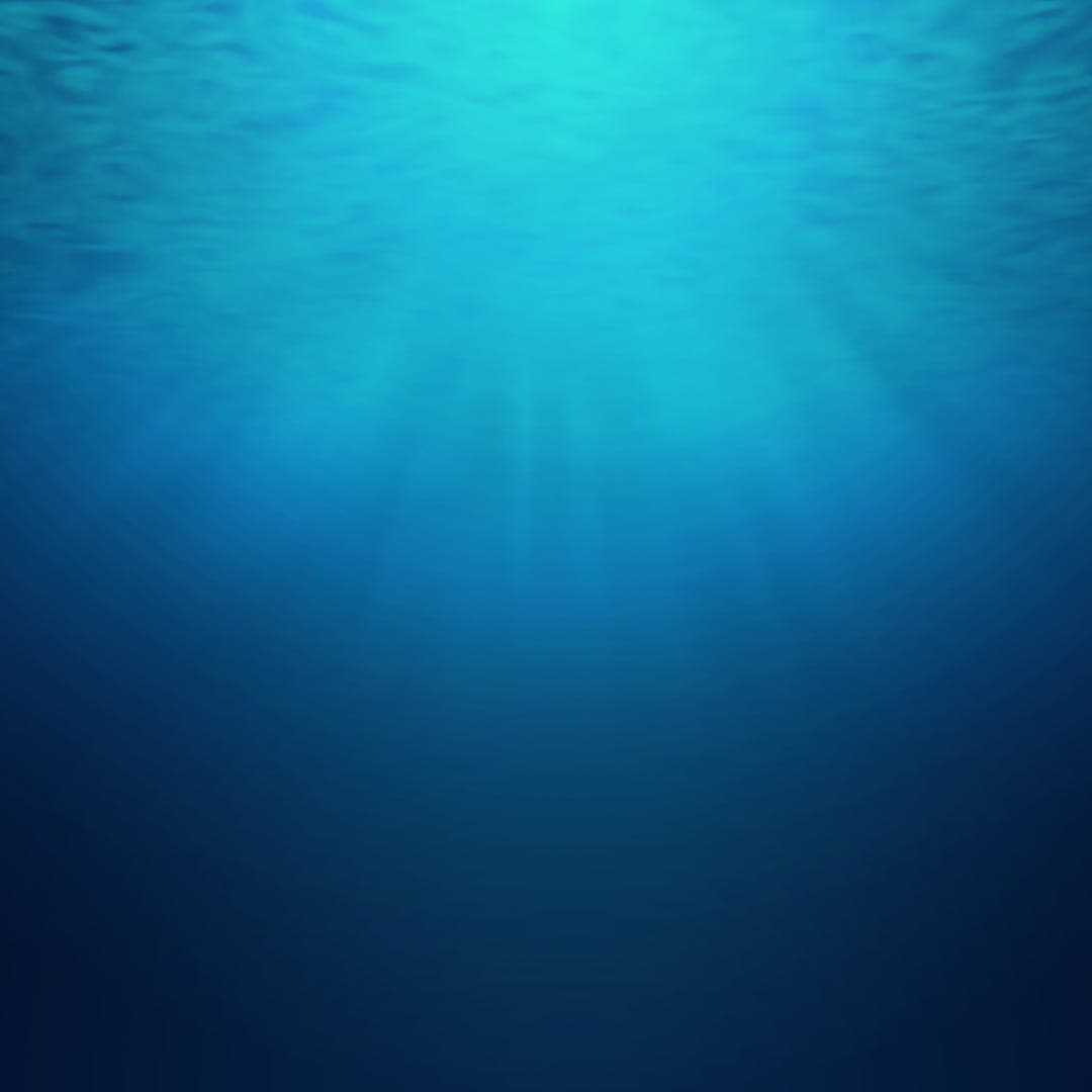 Underwater view with bright turquoise light above deep blue water.