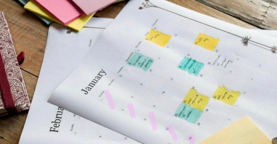 An open planner with monthly calendars, handwritten notes, and colorful sticky notes.
